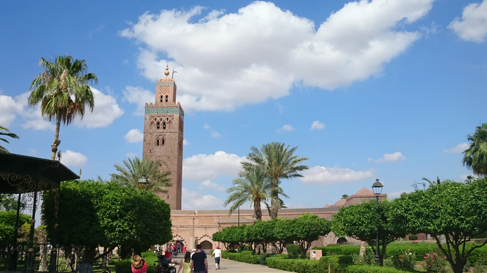 The sandstone minaret of the Koutoubia Mosque in Marrakech rising above palm trees and gardens under a blue sky