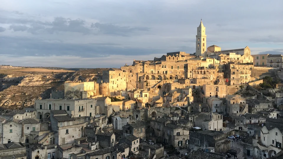 Golden evening light on the stone houses of the Sassi di Matera with the cathedral bell tower rising above