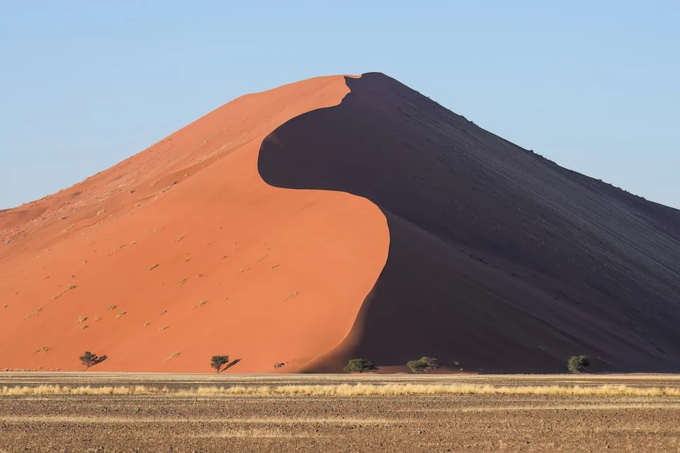 Red sand ridge of Dune 45 in Sossusvlei glowing at sunrise