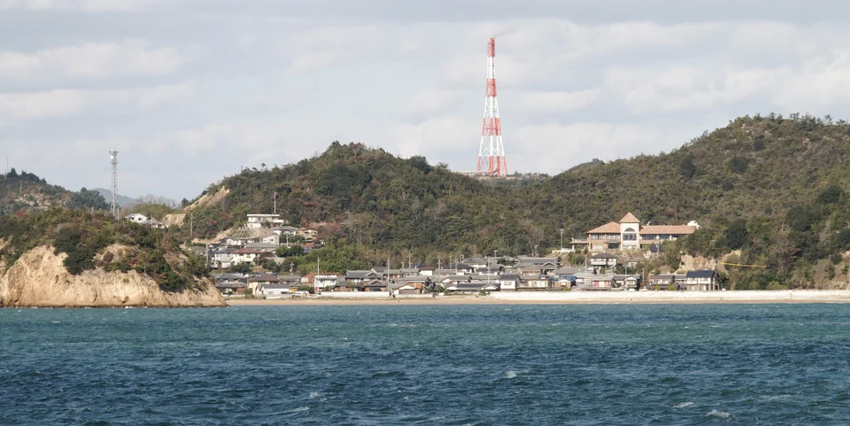 Maisons en bord de mer et collines boisées vues depuis l'eau à Naoshima, dans la mer intérieure de Seto