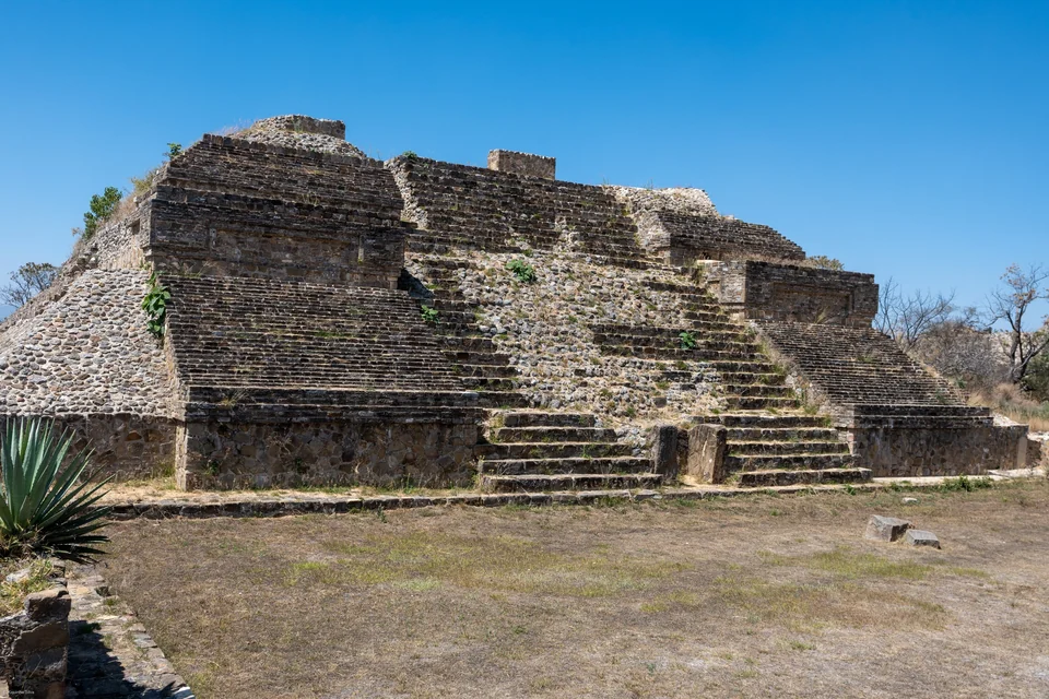 Gestufte Steinplattform in der archäologischen Stätte Monte Albán bei Oaxaca-Stadt mit einer Agave im Vordergrund