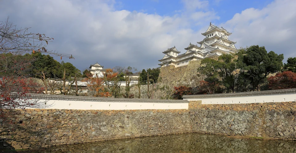 White main keep of Himeji Castle rising above stone walls and trees