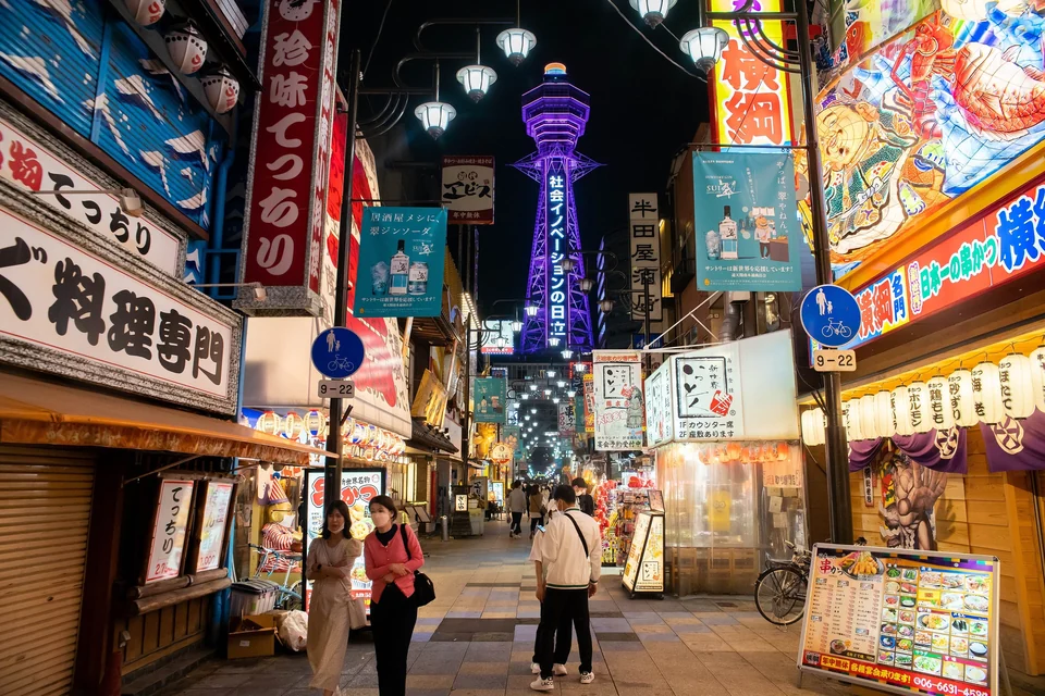 Tsutenkaku Tower and lit signs above the streets of Shinsekai in Osaka at night