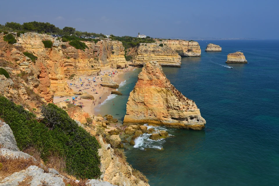 Golden limestone cliffs and a sheltered sandy beach with clear turquoise water at Praia da Marinha, Algarve, Portugal