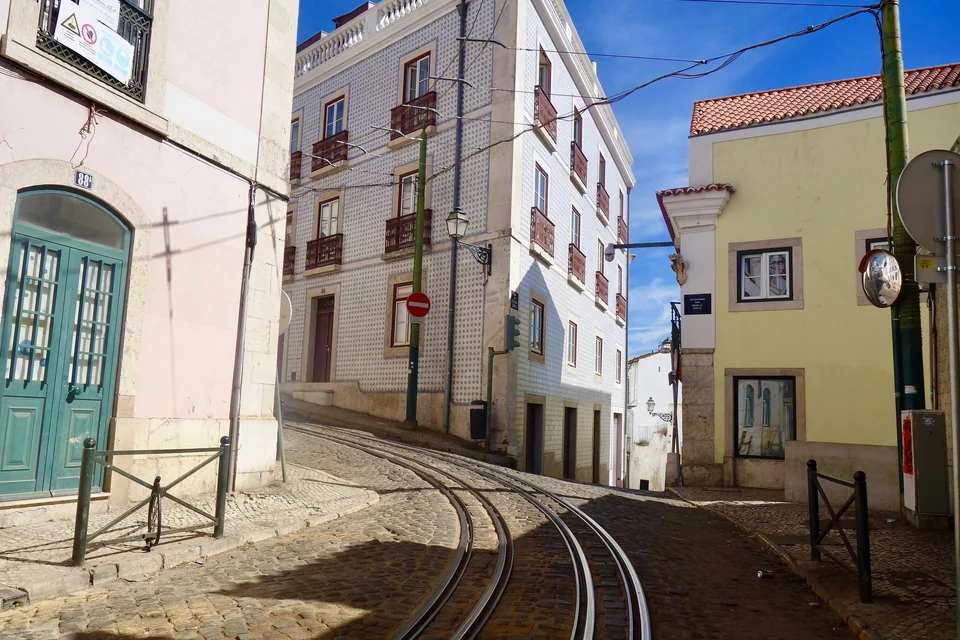 Yellow tram on route 28 climbing a narrow street in the Alfama district of Lisbon, Portugal