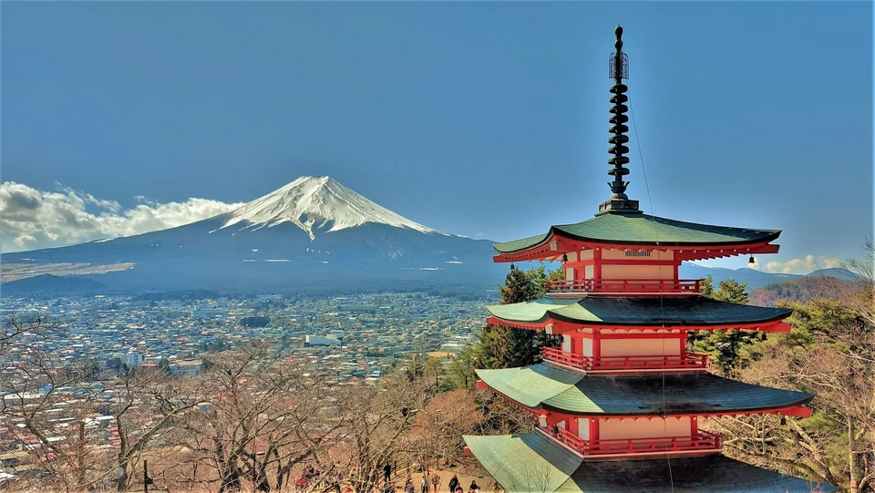 Five-story Chureito Pagoda on a wooded hillside with snow-capped Mount Fuji rising behind it