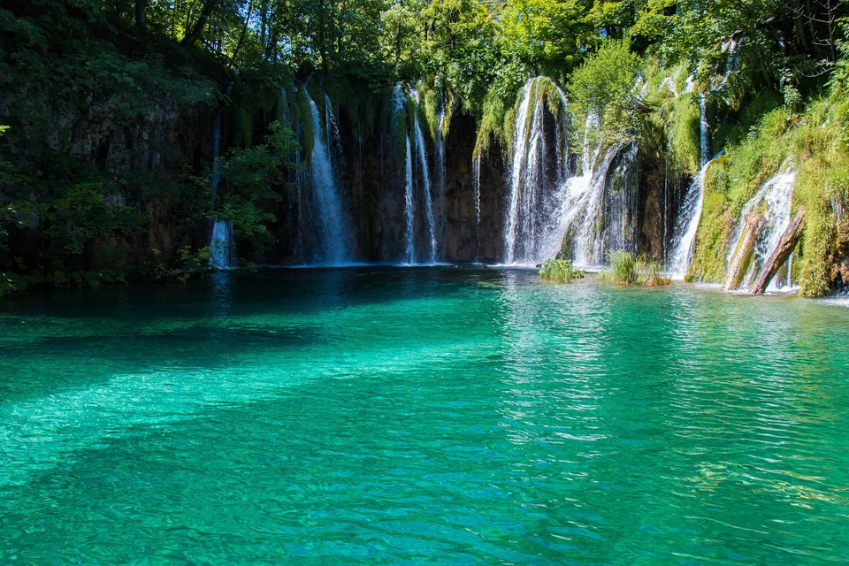 Lago turquesa al pie de una cortina de pequeñas cascadas en el Parque Nacional de los Lagos de Plitvice, Croacia