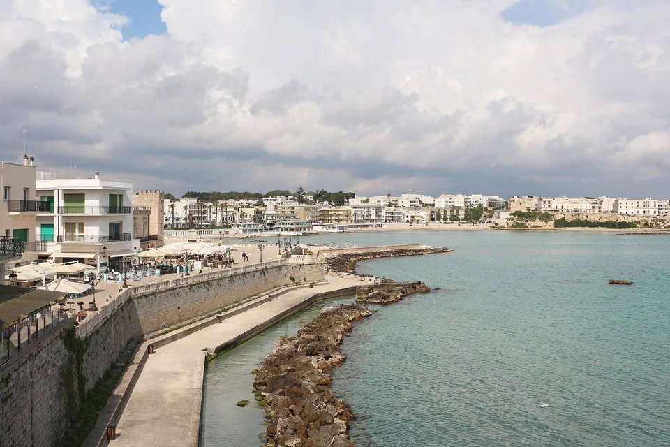 Otranto seafront promenade along the old town walls with turquoise Adriatic water and the town beach beyond