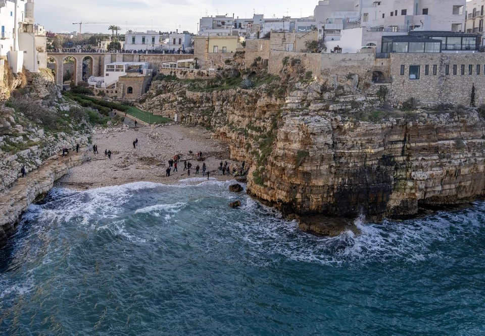 Lama Monachile cove in Polignano a Mare, a pebble beach between limestone cliffs topped by old town houses