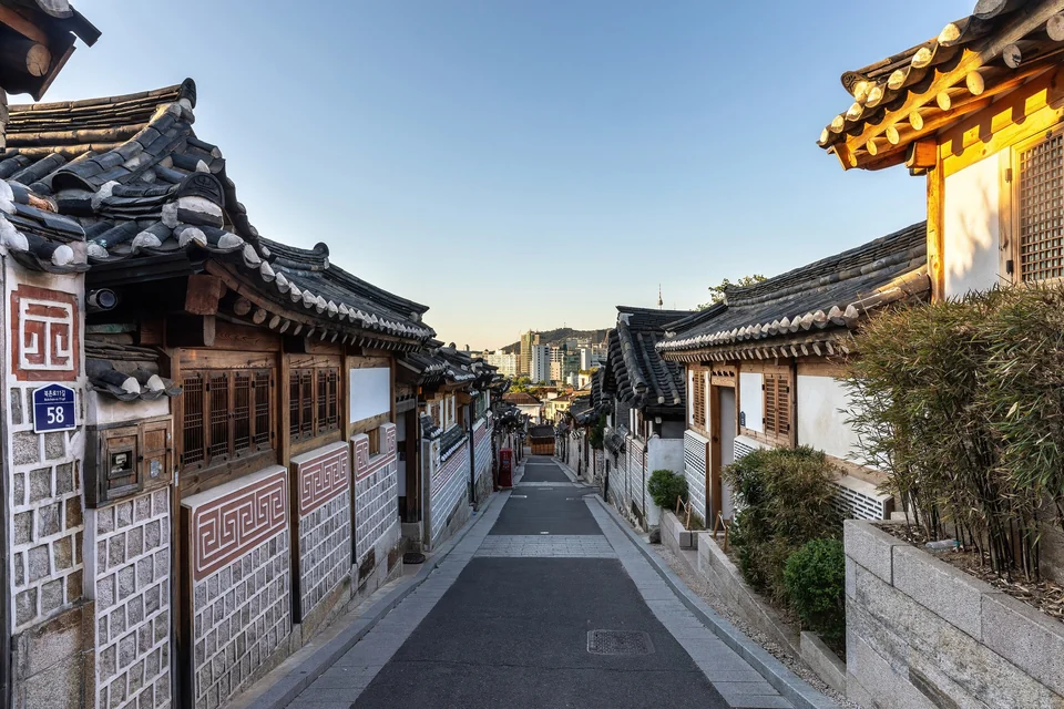 Traditionelle Hanok-Häuser säumen bei Sonnenaufgang eine abfallende Straße im Hanok-Dorf Bukchon in Seoul