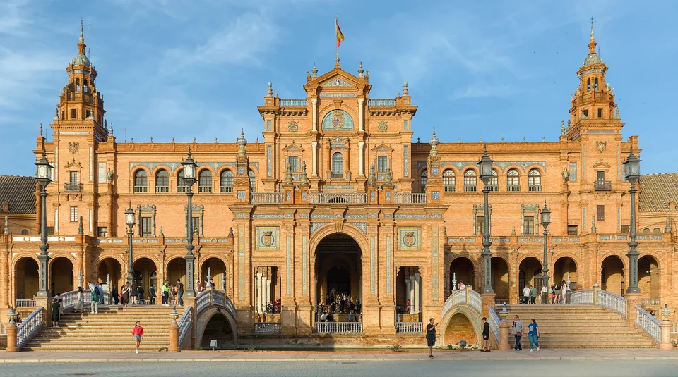 Edificio curvo de ladrillo de la Plaza de España de Sevilla con torres, un canal y un puente a la luz de última hora de la tarde