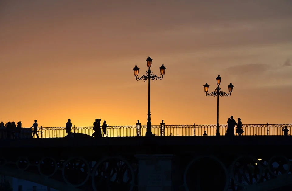 El Puente de Triana sobre el río Guadalquivir en Sevilla, al anochecer, con los edificios iluminados a lo largo de la orilla