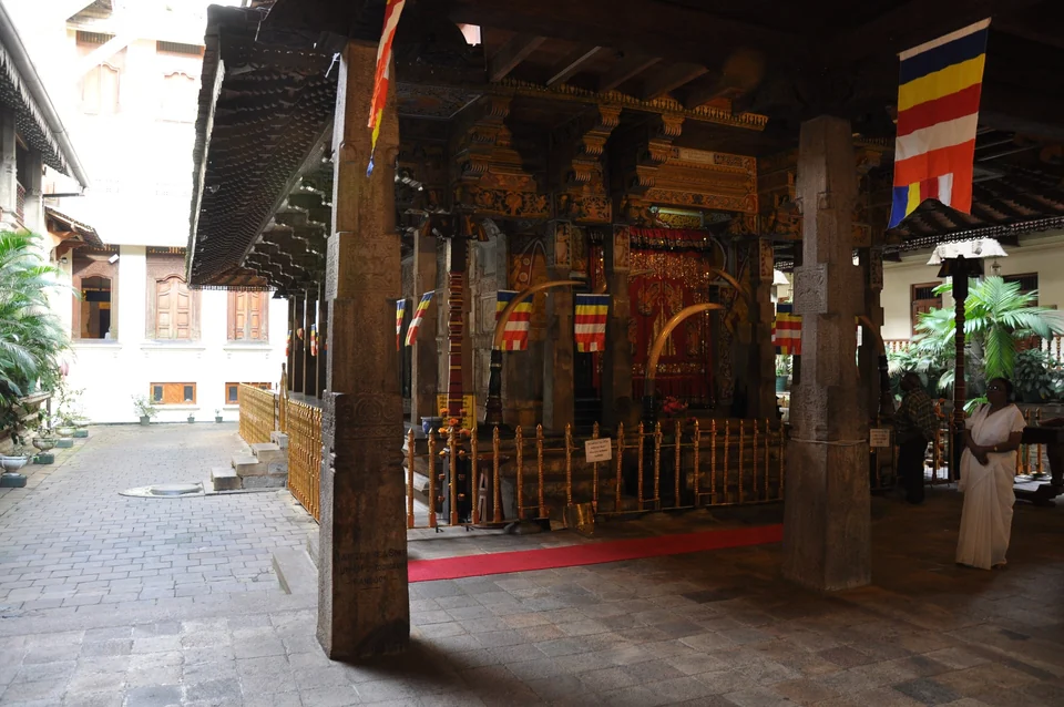 Carved wooden shrine with elephant tusks and Buddhist flags inside the Temple of the Sacred Tooth Relic in Kandy