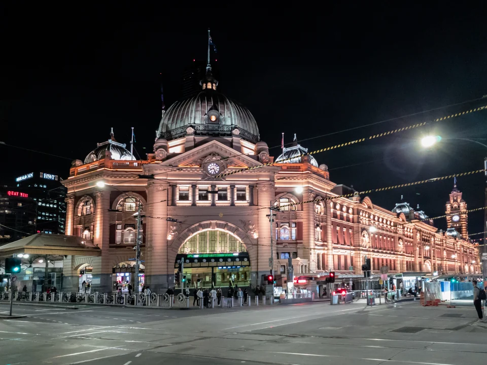 Flinders Street Station in Melbourne lit up at night with its dome and clock tower