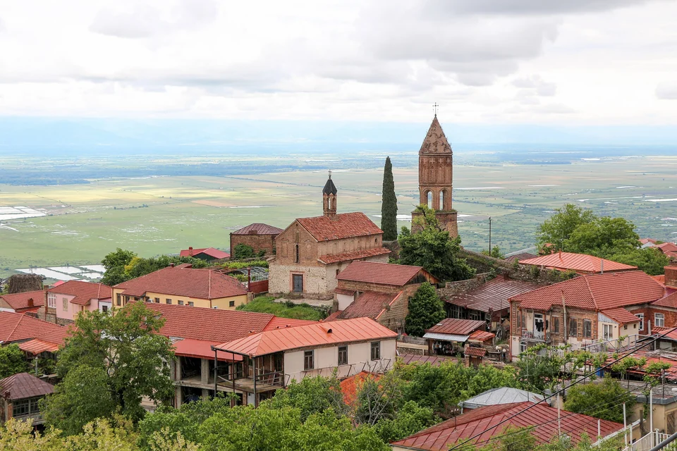 Red roofs and a brick bell tower in Sighnaghi with the flat Alazani Valley stretching to the horizon