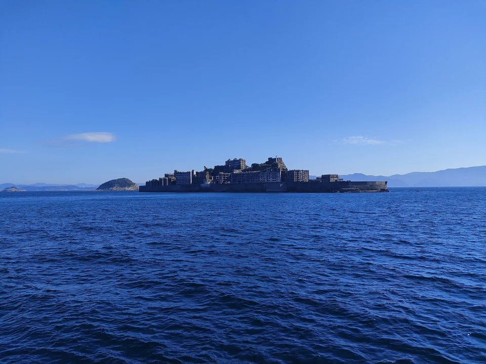 Distant view of Gunkanjima (Hashima Island) on the horizon across deep blue sea off Nagasaki