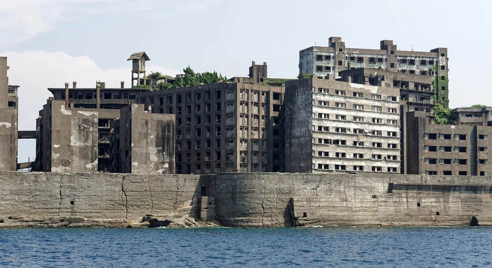 Abandoned concrete apartment blocks rising behind the seawall of Gunkanjima (Hashima Island) near Nagasaki