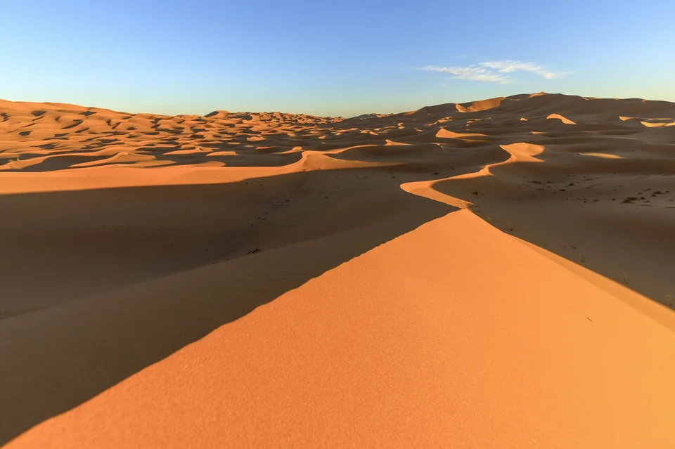 Sharp-crested orange sand dunes of Erg Chebbi in the Moroccan Sahara in low evening light