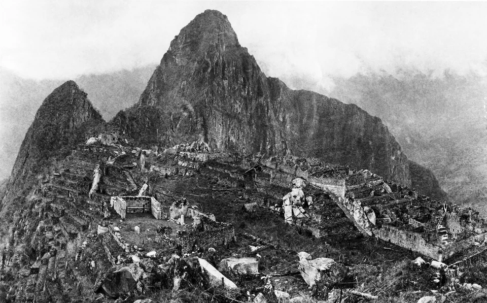 Black-and-white 1912 photo by Hiram Bingham of partly cleared Machu Picchu ruins below Huayna Picchu