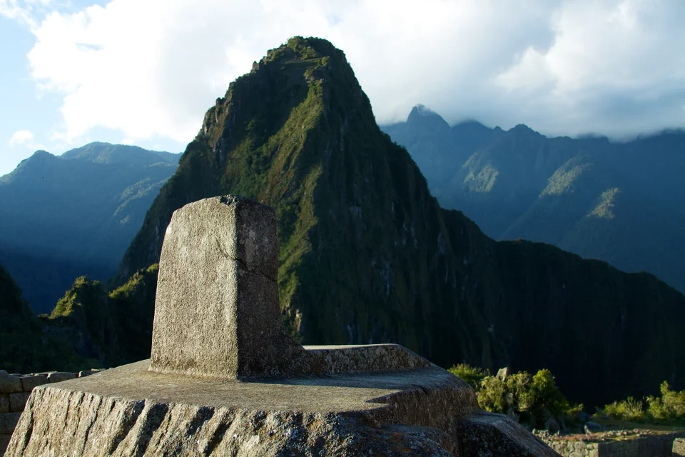 Carved granite Intihuatana stone at Machu Picchu with the peak of Huayna Picchu rising behind