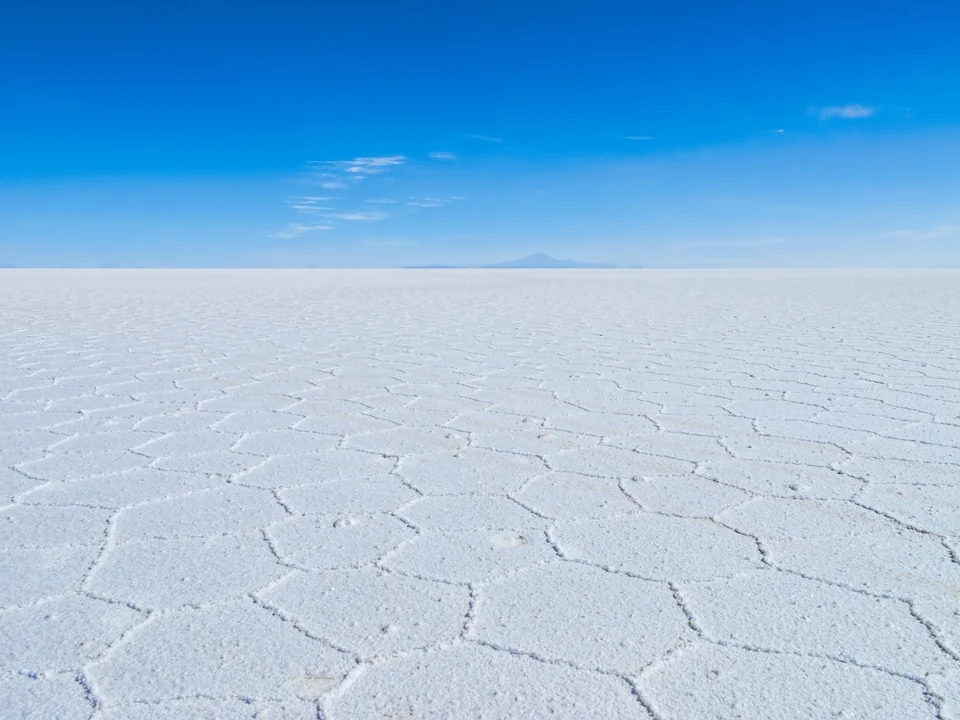 Hexagonal salt crust patterns stretching to the horizon under a blue sky on the dry Salar de Uyuni