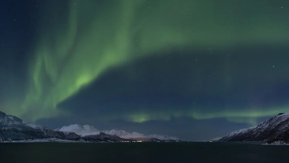 Northern lights flowing over Lyngenfjord and snowy mountains of the Lyngen Alps in northern Norway