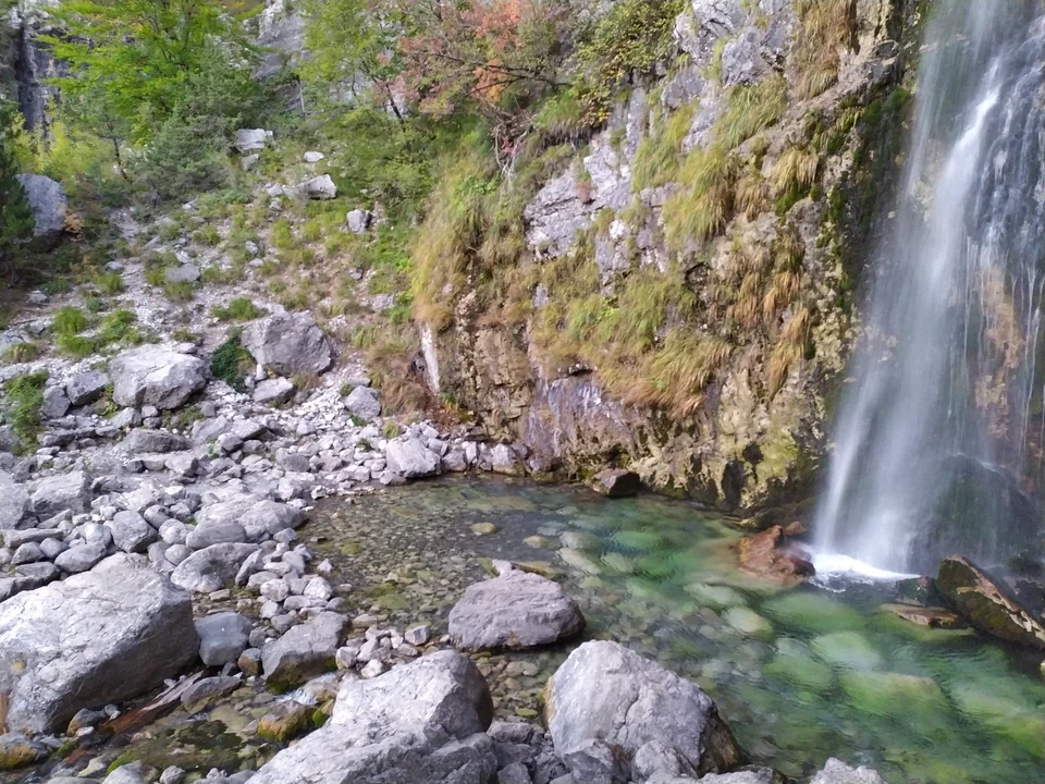 The Grunas waterfall dropping into a green pool among boulders near Theth in northern Albania