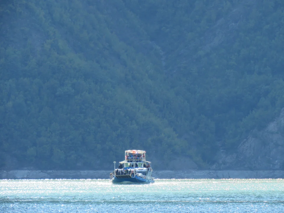 The Lake Komani ferry carrying passengers across the reservoir between forested hills in northern Albania