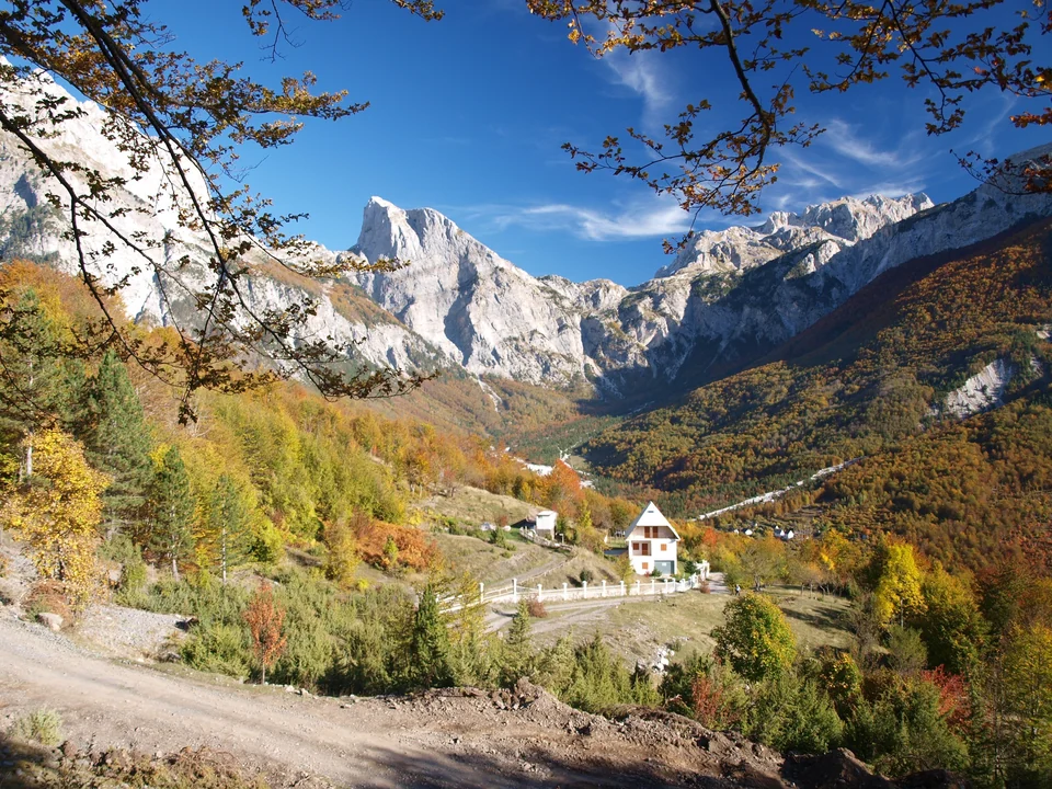 Autumn forest and white limestone peaks above a mountain valley in the Albanian Alps near Theth, Albania