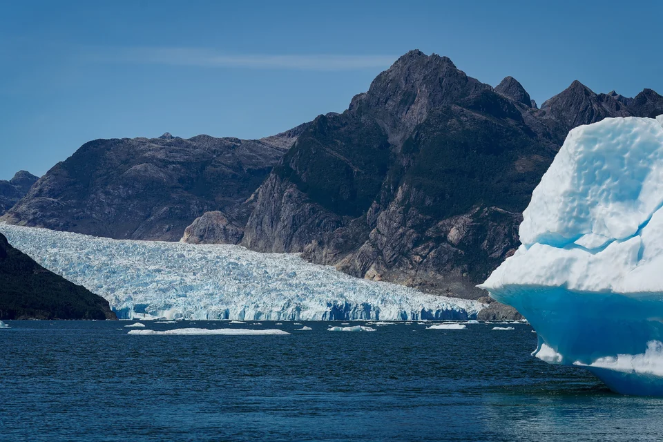 Kalben vor dem San-Rafael-Gletscher mit einem Eisberg, der in der Laguna San Rafael, Aysén, Chile treibt.
