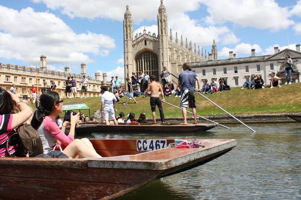 Punts on the River Cam passing King’s College Chapel and lawns crowded with visitors in Cambridge