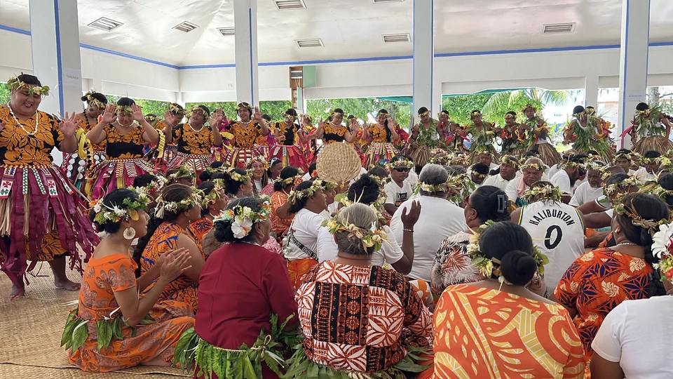Dancers in floral garlands and patterned costumes performing a fatele in a meeting hall on Funafuti, Tuvalu