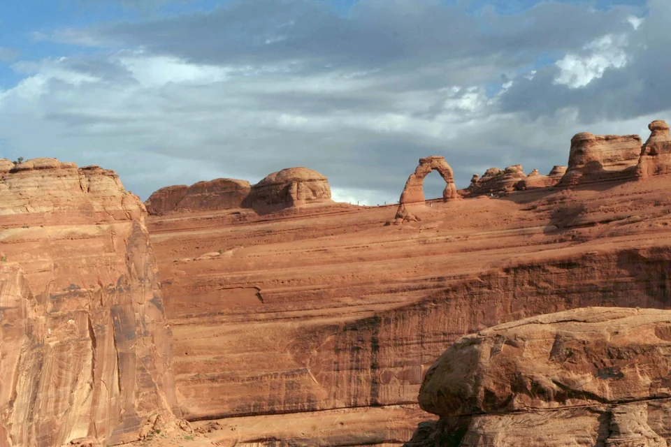 Delicate Arch standing alone on a slickrock bowl in Arches National Park, Utah, seen from the viewpoint