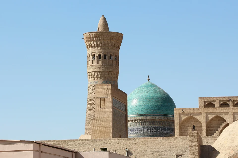 The brick Kalyan Minaret in Bukhara beside the turquoise dome of the Mir-i-Arab Madrasa