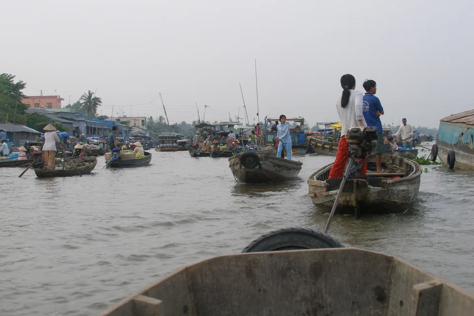 Wooden boats laden with fruit and traders in conical hats at a floating market near Can Tho, Mekong Delta