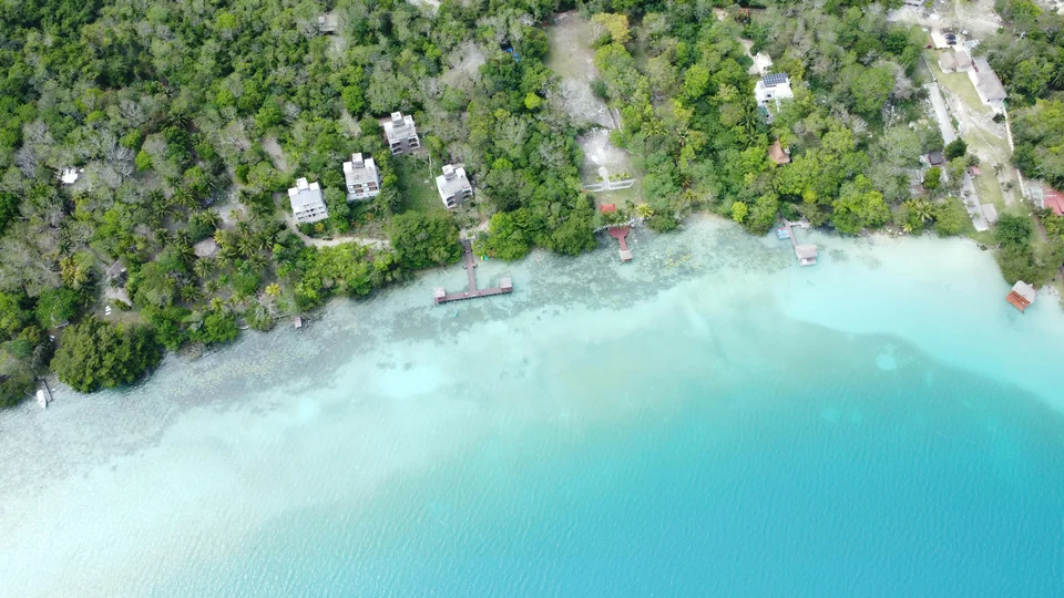 Flaches, vielfarbiges Wasser und ein Holzsteg an der Bacalar-Lagune in Quintana Roo, Mexiko