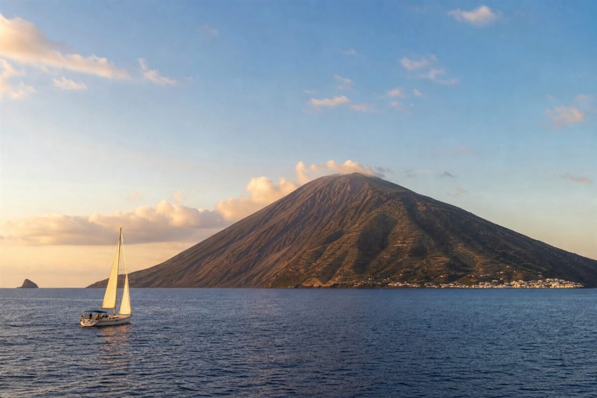 Sailboat passing Stromboli in the Aeolian Islands Italy at sunset